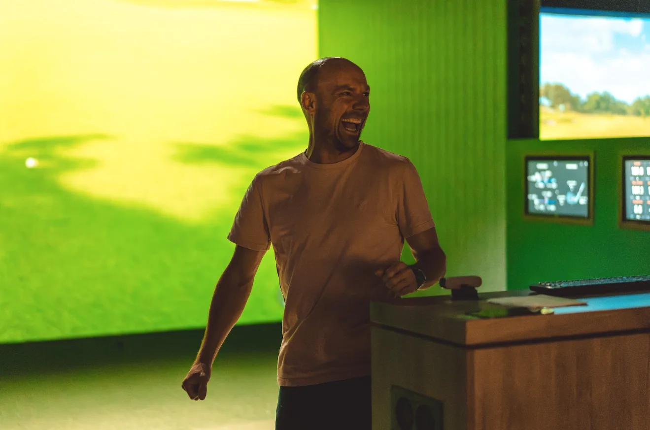 Member celebrating a shot in a TrackMan simulator bay